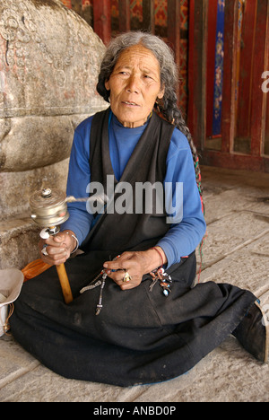 Ritratto di un anziano tibetano donna la filatura di una ruota di preghiera Monastero di Samye Tibet Foto Stock