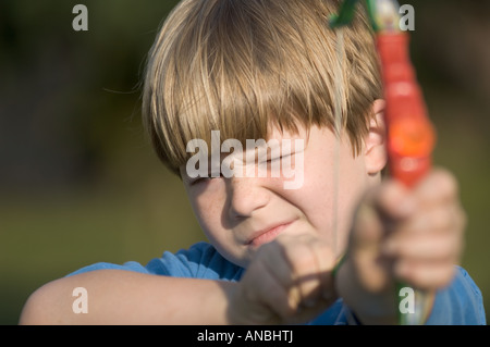 Giovane ragazzo giocattolo di tiro arco e frecce ventosa a giocare i bambini sporting tenendo scopo pratica su target Foto Stock