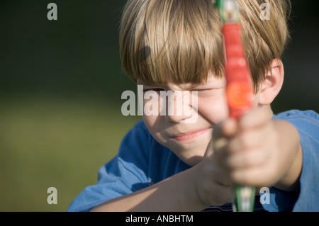 Giovane ragazzo giocattolo di tiro arco e frecce ventosa a giocare i bambini sporting tenendo scopo pratica su target Foto Stock