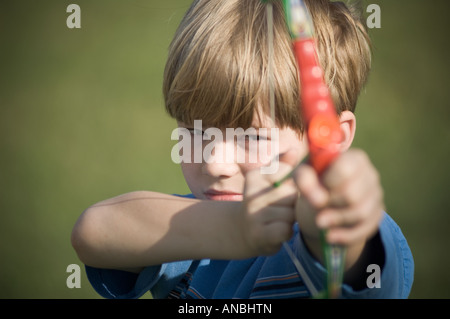 Giovane ragazzo giocattolo di tiro arco e frecce ventosa a giocare i bambini sporting tenendo scopo pratica su target Foto Stock