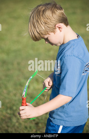 Giovane ragazzo giocattolo di tiro arco e frecce ventosa a giocare i bambini sporting tenendo scopo pratica su target Foto Stock