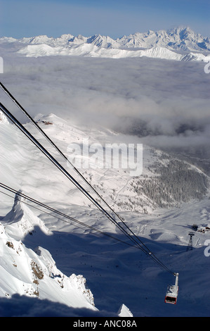 Cable car going up mountain with snow covered mountains in background Foto Stock