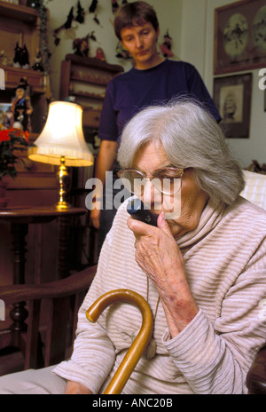 Donna anziana con problemi respiratori utilizza un medico puffer nella propria casa con un accompagnatore REGNO UNITO Foto Stock