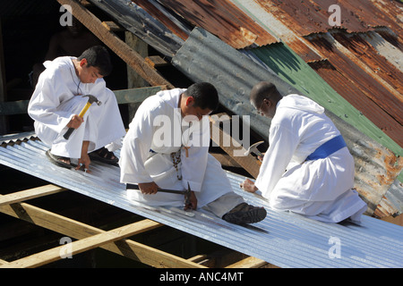 Sacerdoti e Fratelli della cattolica congrigation 'Missionaries dei poveri" (MOP) la riparazione di tetti di popolazioni povere case, Giamaica Foto Stock