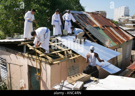 Sacerdoti e Fratelli della cattolica congrigation 'Missionaries dei poveri" (MOP) la riparazione di tetti di popolazioni povere case, Kingston, Giamaica Foto Stock