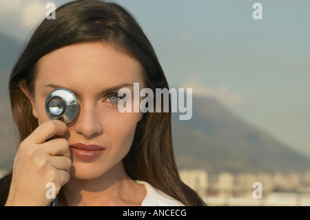 Giovane donna tenendo uno stetoscopio over eye Foto Stock