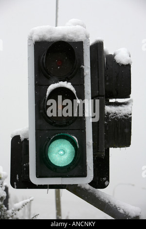 Il semaforo verde coperto di neve durante la bufera di neve Foto Stock