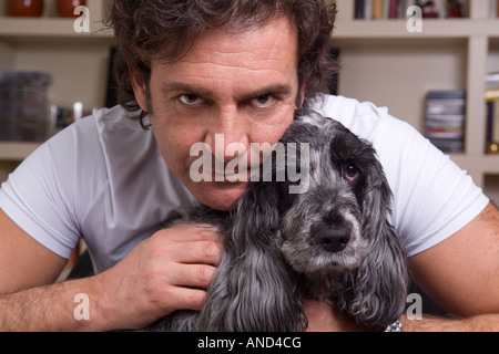 L'uomo abbraccia il suo proprio cane indoor Foto Stock