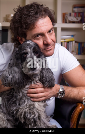 L'uomo abbraccia il suo proprio cane indoor Foto Stock