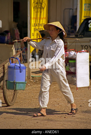 Mobile chiosco caffetteria donna indigena con il tradizionale cappello di paglia portano ambulatoriamente bar sullo spallamento Vang Vieng Laos del sud-est asiatico Foto Stock