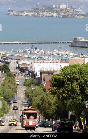 San Francisco cable car o carrello scendendo una collina che domina la prigione di Alcatraz e Fishermens Wharf Foto Stock