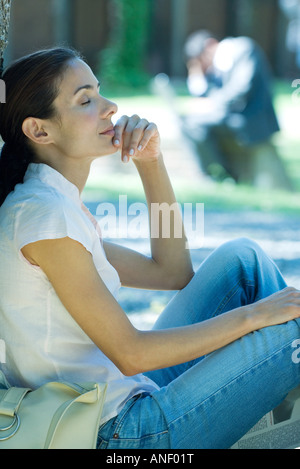 Donna seduta su un suolo, Pendente ritornare a occhi chiusi Foto Stock