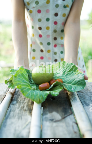 Giovane donna tenendo fuori produzione fresca, tagliata Foto Stock