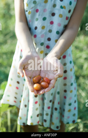 Giovane donna tenendo fuori i pomodori ciliegia, ritagliato Foto Stock
