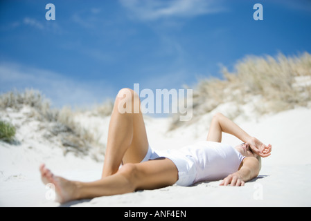 Giovane donna sdraiata sulla spiaggia Foto Stock