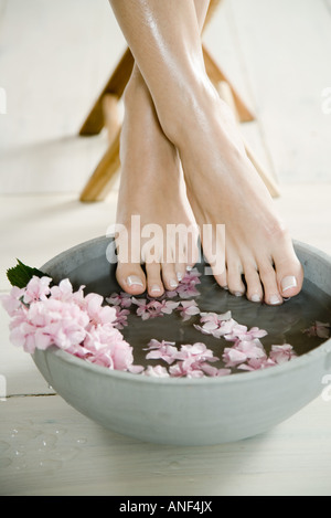 Giovane donna di piedi e floreali bagno del piede Foto Stock
