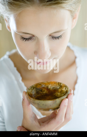 Donna che mantiene fino piccolo recipiente al naso, close-up Foto Stock