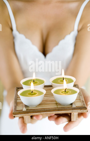 Donna tenendo fuori il vassoio di candele, ritagliato Foto Stock