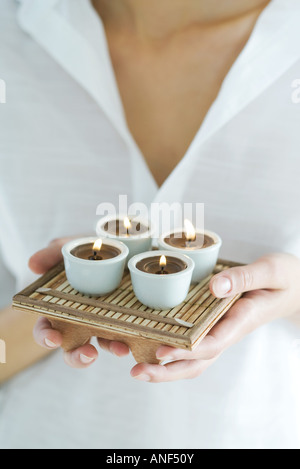Donna tenendo il vassoio di candele, close-up, ritagliato Foto Stock