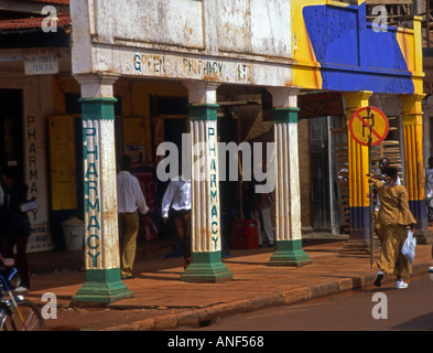 Scena di strada della trafficata area dello shopping e i dettagli di tipica architettura coloniale & colonnato città Jinja Uganda Africa orientale Foto Stock