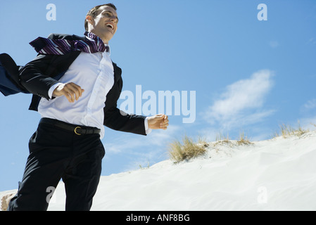 Imprenditore in esecuzione attraverso dune di sabbia a basso angolo di visione Foto Stock