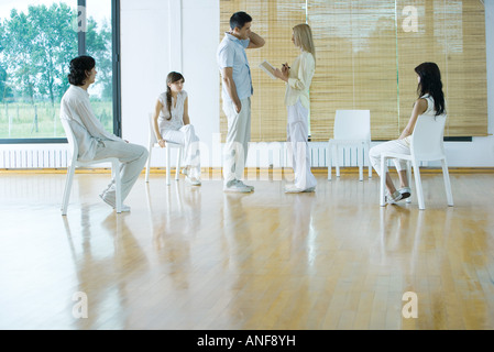 Donna che portano la terapia di gruppo sessione, tenendo notebook, parlando all'uomo Foto Stock