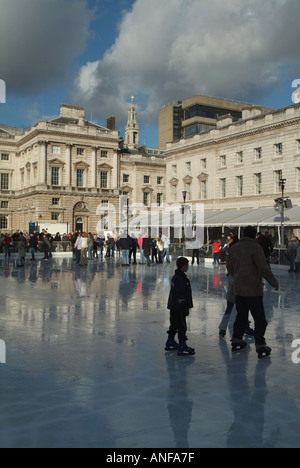 Adulti e bambini pattinatori di ghiaccio con sfondo storico Somerset House Edificio e cortile sulla temporanea pista di pattinaggio invernale Strand Londra Inghilterra Regno Unito Foto Stock