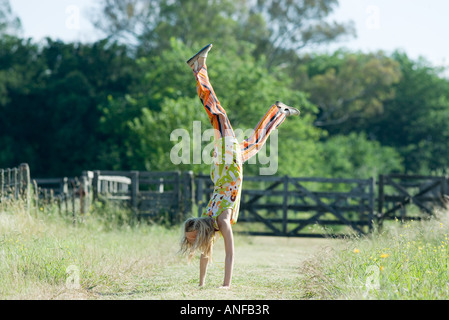 Giovane donna facendo handstand in campo rurale Foto Stock