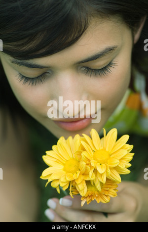 Giovane donna profumati fiori a occhi chiusi ad alto angolo di visione, ritagliato Foto Stock