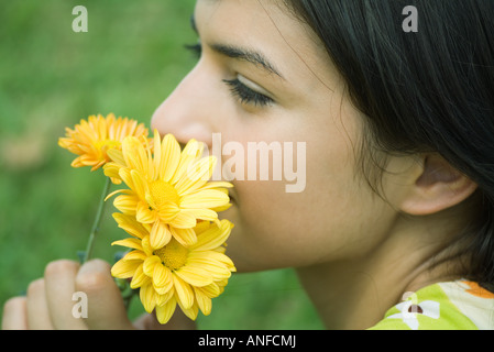 Giovane donna fiori profumati, guardando lontano, profilo Foto Stock