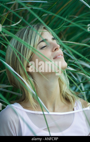 Giovane donna tra le fronde, testa indietro, occhi semi-aperto Foto Stock