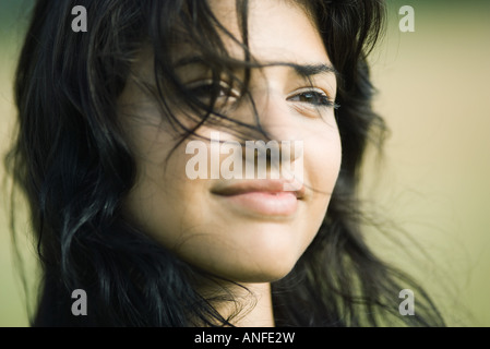 Giovane donna con capelli soffiando attraverso il suo volto sorridente, ritratto Foto Stock
