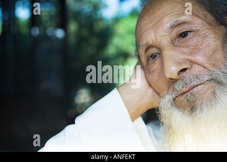 Uomo anziano testa pendente contro il lato che guarda lontano, close-up Foto Stock