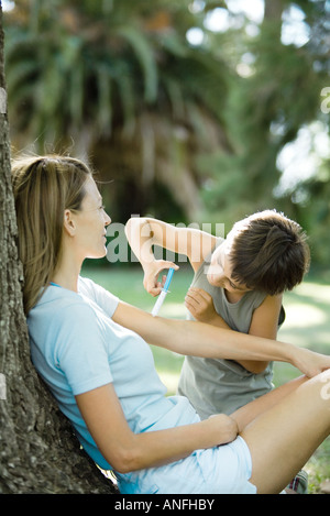 Madre e figlio all'aperto, ragazzo finge di dare donna shot Foto Stock