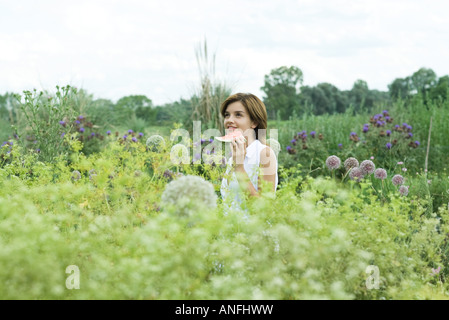 Giovane donna in piedi in giardino, azienda fetta di cocomero Foto Stock
