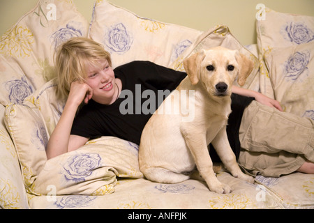 13-anno-vecchio ragazzo e quattro-mese-vecchio labrador-golden retriever cucciolo sul lettino, Vancouver, British Columbia, Canada. Foto Stock