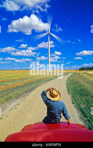 L'uomo sul carrello la visualizzazione di turbine eoliche in canola field, vicino San Leon, Manitoba, Canada. Foto Stock