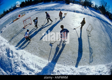 Ragazzi giocare ad hockey su pista di pattinaggio all'aperto, Winnipeg, Manitoba, Canada. Foto Stock