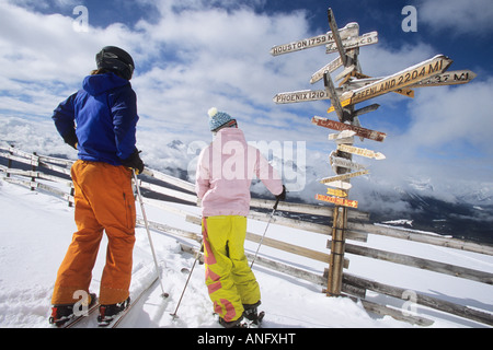 Due gli sciatori ammirando la vista da sopra molti vicini picchi. Essi sono anche guardando il post intonacate con direzioni e dis Foto Stock