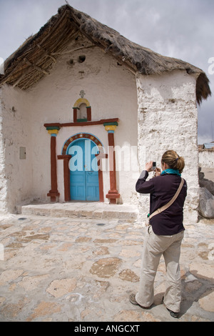 Turistica prendendo una fotografia della vecchia chiesa di Parinacota Cile nelle Ande altitudine di circa 4500 metri Foto Stock