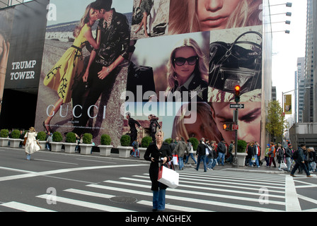 I turisti sulla Fifth Avenue a New York davanti al Trump Tower dove un nuovo negozio di Gucci è pubblicizzato Foto Stock