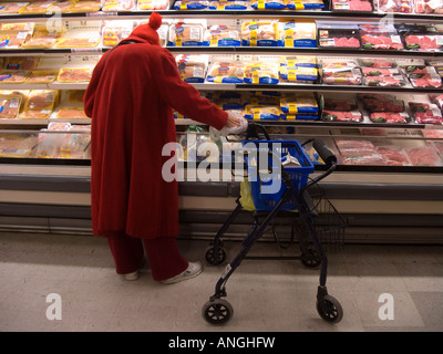 Un Senior Citizen negozi per pollo nel dipartimento di carne di un supermercato Foto Stock