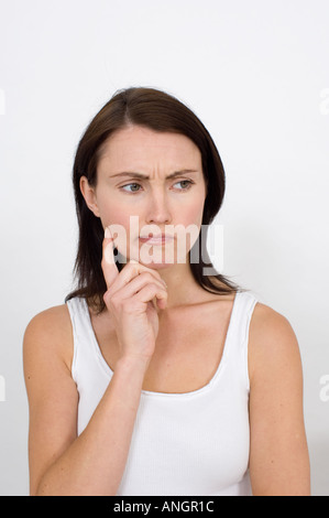 Donna attraente guardando pensosa e triste Foto Stock