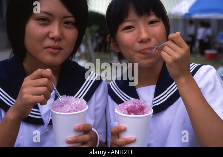 Due di alta scuola ragazze in uniforme di mangiare ghiaccio rasata Okinawa in Giappone Foto Stock