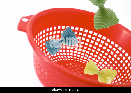 Red setaccio da cucina con pasta la caduta verso il basso a partire da sopra Foto Stock