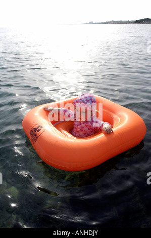 Baby girl orange salvagente anello di gomma Oceano Mare Viaggi turismo vacanze la libertà di svago spensierato in verticale Foto Stock