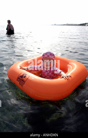 Baby girl orange salvagente anello di gomma Oceano Mare Viaggi turismo vacanze la libertà di svago spensierato in verticale Foto Stock
