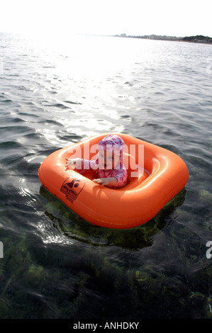 Baby girl orange salvagente anello di gomma Oceano Mare Viaggi turismo vacanze la libertà di svago spensierato in verticale Foto Stock