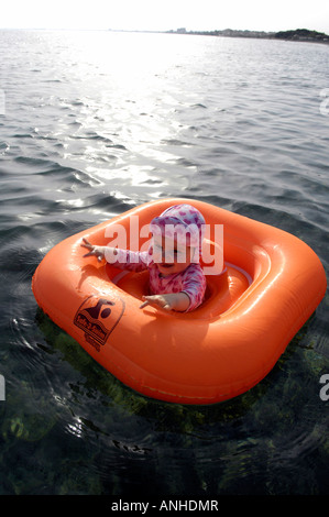 Baby girl orange salvagente anello di gomma Oceano Mare Viaggi turismo vacanze la libertà di svago spensierato in verticale Foto Stock