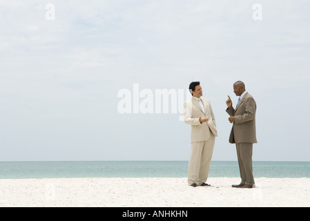 Due imprenditori in piedi faccia a faccia presso la spiaggia di conversazione Foto Stock